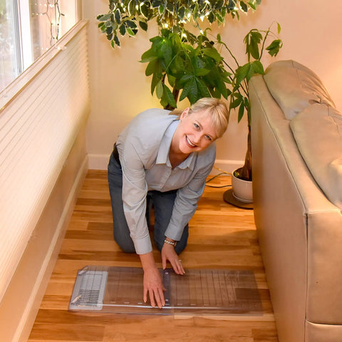 Woman installing Magnetic Vent Extender for Under Furniture with Adjustable 17 to 33 Inch Length under sofa on wooden floor