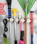 Mop and Broom Holder Wall Mount with Five Slots and Six Hooks, holding various tools in a garage or home setting, off white.