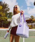 Lilac Breeze 11 Qt Tag-Along Cooler With Strapped Crossbody Carry shown on tennis court