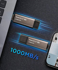 Blazing Fast 1TB X2 Max Portable SSD With 1000 MB Per Second Transfer, Type C And A USB 3 Gen2 next to laptop and smartphone.