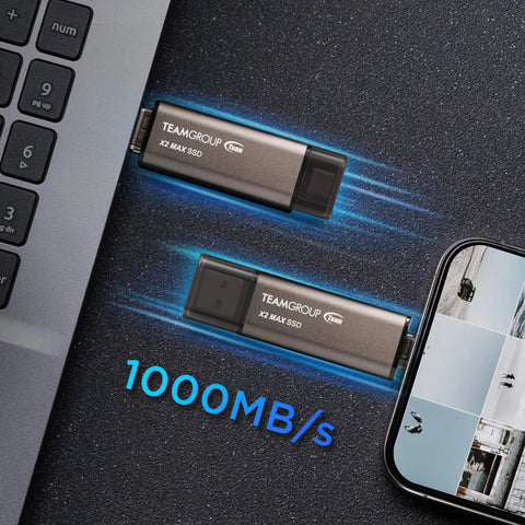 Blazing Fast 1TB X2 Max Portable SSD With 1000 MB Per Second Transfer, Type C And A USB 3 Gen2 next to laptop and smartphone.