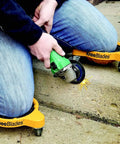 User wearing Heavy Duty Knee Blades With Gel Cushions And Three Casters For Unisex Adults, using grinder on concrete step.