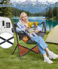 Person seated in grey oversized hammock camping chair with adjustable backrest, reading by a lake. Heavy duty, 350 lbs capacity.