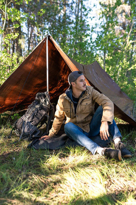 Person sitting under Rip Stop Tarp 8 By 10 Feet Heavy Duty Waterproof Brown Outdoor Shelter For Camping And Backyard Use, Lightweight