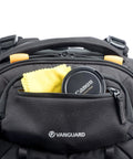 Close-up of front pocket of Eight Wheel Spinner Camera Backpack for DSLRs and Gear with lens cap and cleaning cloth visible.