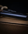 Close-up of Go-To 5.9 Inch Ferro Rod Fire Starter Kit with wooden handle and sheath, resting on brown surface, showing rod detail.