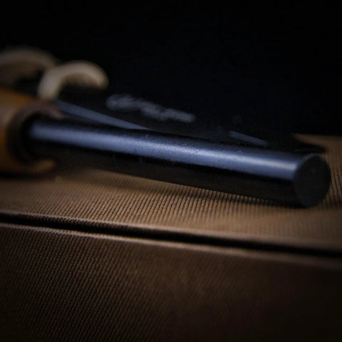 Close-up of Go-To 5.9 Inch Ferro Rod Fire Starter Kit with wooden handle and sheath, resting on brown surface, showing rod detail.