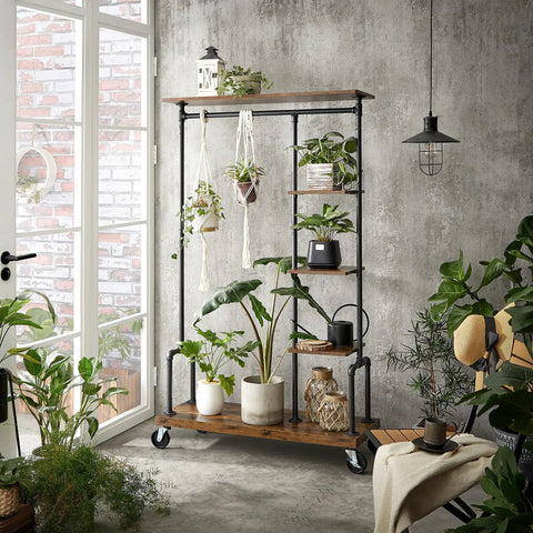 Smooth Rolling 5 Tier Clothes Rack With Industrial Pipe Frame And Rustic Brown Shelves For Organizing Wardrobe Essentials And Flexing Your Daily Fits At Home displaying potted plants in a modern setting.