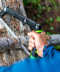 Close-up of folding camp saw with 12-inch blade cutting wood, showcasing flat pocket ready design and bright green accents.