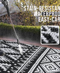 Waterproof Reversible Outdoor Rug 5x8 Ft Made From Recycled Plastic Straws black and white pattern being cleaned outdoors