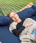 Person relaxing in Big Comfy Outdoor Hammock For Trees And Stands Navy Blue With Fade Resistant Two Layer Quilted Fabric And Poly Fiber Fill