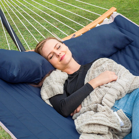 Person relaxing in Big Comfy Outdoor Hammock For Trees And Stands Navy Blue With Fade Resistant Two Layer Quilted Fabric And Poly Fiber Fill