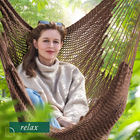 Woman relaxing in an Extra Large Hammock Swing Chair With Spreader Bar For Indoor Or Outdoor Kick Back Relaxing, Handcrafted Rope Hanging Chair.