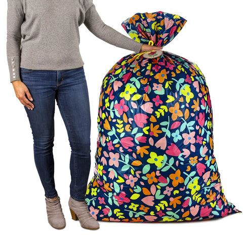 Person holding Giant 56 Inch Plastic Gift Bag with pink and yellow floral print, ideal for large gifts like ottomans and more.