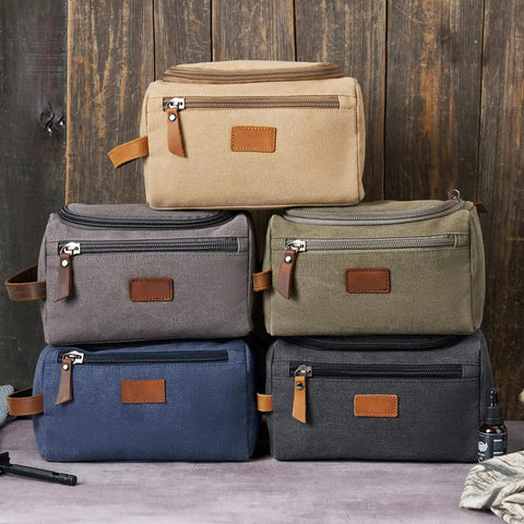 Stack of rugged mountain pattern toiletry bags for men with large capacity, water resistant, canvas Dopp kits in earthy colors.