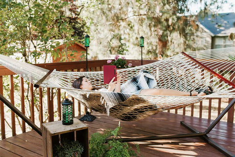 Woman on hammock on deck with Heavy Duty Cast Iron Torch Stand Built Like A Tank For Outdoor Lighting in the background