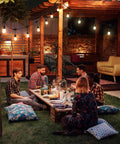 Outdoor dining scene with 48 Ft Outdoor String Lights With 15 Waterproof LED E26 Bulbs Commercial Grade Patio Cafe Lighting For Backyard Ambience Durable Shatterproof Plastic Bulbs Built To Withstand Rain And Sun illuminating a group of friends.