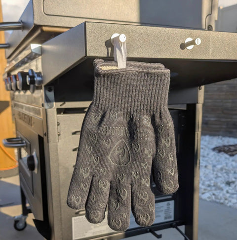 932F Extreme Heat Resistant Oven Gloves With Fingers For Grilling And Cookin In The Kitchen hanging on BBQ grill