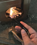 Hand using All Weather Fire Starter Kit With Paraffin Wax Infused Hemp Wicks And Aluminum Bellow Sleeve 60 Minute Burn Waterproof Rope Match