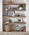 Wooden shelves with decorative items and plants, wicker basket and cushions, part of a modern living room setup.