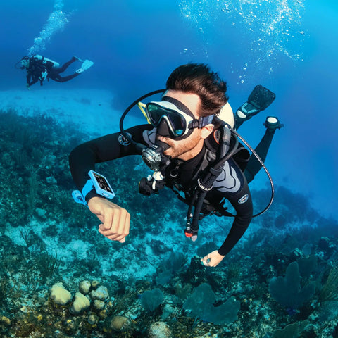 Diver underwater using Luna 2.0 AI Wrist Dive Computer With Bluetooth, Easy Read Wide LCD, visible on wrist, coral reef in background