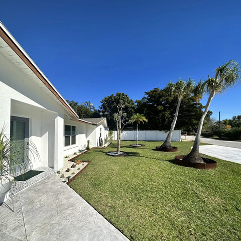 Suburban yard with palm trees enclosed by the Built Tough Sturdy Circular Tree Ring Edging Kit For Landscapes Made With Corten Steel.