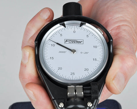 Fowler dial bore gauge in black housing with white dial, held in hand; Fowler logo visible.