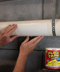 Hands applying heavy duty rubberized waterproof tape that seals leaks and patches it all for indoor and outdoor use white 8 inch by 5 foot pack of 2 tough as nails patch job for home RV roofs plumbing and pool repairs on a pipe.