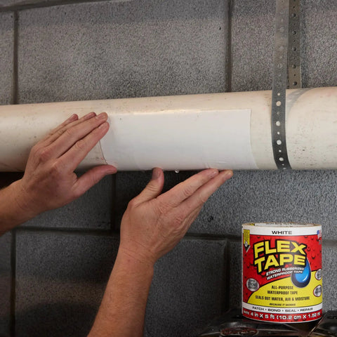 Hands applying heavy duty rubberized waterproof tape that seals leaks and patches it all for indoor and outdoor use white 8 inch by 5 foot pack of 2 tough as nails patch job for home RV roofs plumbing and pool repairs on a pipe.