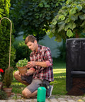 Man gardening next to black outdoor compost bin for garden 34 gallon reusable yard waste bag, big capacity for kitchen scraps and plant waste.