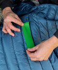 Applying Tenacious Tape 3 Inch By 20 Inch Nylon Fabric Repair Tape Patch For Holes And Rips In Jackets Rain Gear Tents Sleeping Bags And Outdoor Gear Peel And Stick No Heat Or Sewing Required Black 1 Roll on a blue sleeping bag