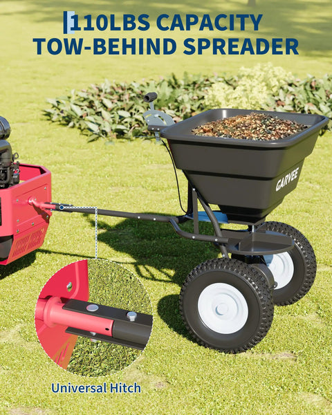 Tow Behind Broadcast Spreader With 110 Lb Hopper Universal Hitch shown attached to red tractor on grass