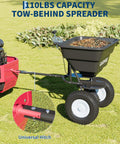 Tow Behind Lawn Broadcast Spreader With Universal Hitch 85 Lb Poly Hopper attached to mower in garden