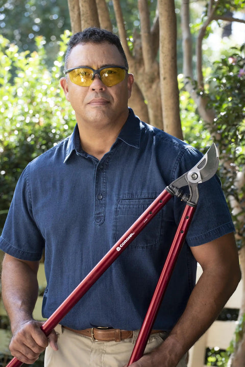 Person holding 36 Inch Branch Cutter Loppers With Aluminum Handles And Dual Arc Bypass Blade in a garden setting.