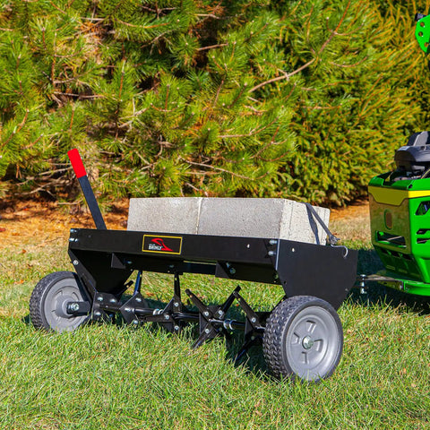 Tow Behind Plug Aerator with Folding Easy Store Tow Bar, 42 Inch Working Width attached to lawn tractor, on grass.
