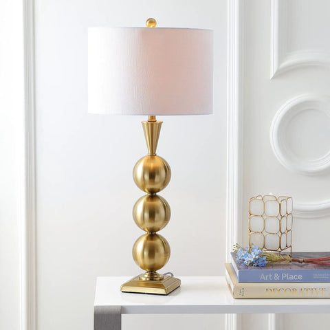 Brass Gold Stacked Orb LED Table Lamp 33 Inch Tall With White Linen Drum Shade on table next to books in living room