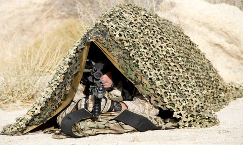 Multicam Camo Netting for Tactical Shelters and SmartFrame Systems in desert setup with soldier underneath aiming for concealment