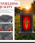 Stone-textured solar cemetery light with red cross panel during sunset
