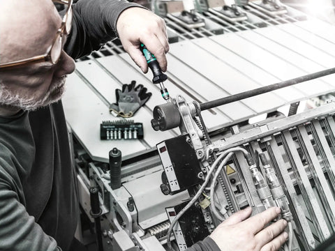 Person using Kraftform Torque Screwdriver Set With Rapidaptor Bitholder, 0.3-6.0 Nm, 27 Pieces on machinery for precise adjustments.