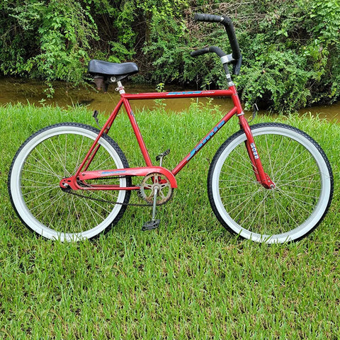 Red bicycle with 26 Inch Cruiser Bike Tire Replacement Set With Two Tubes And Levers, white sidewall tires, parked on grass