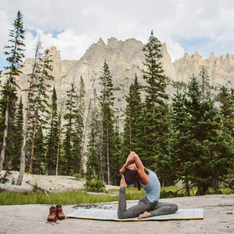 Person doing yoga on Z Lite Original Camping And Backpacking Sleeping Pad Lightweight Closed Cell Foam Ground Pad in mountains.
