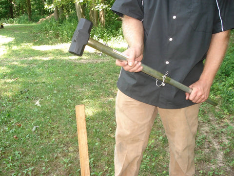 Man holding Handle All Multi Purpose Tool Workhorse with telescoping handle, full-size sledge hammer head, outdoors.