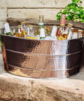 Aspen Heavy-Duty Oval Stainless Steel Drink Cooler For Parties 25-Quart Large Ice Bucket, filled with bottles, on a outdoor surface