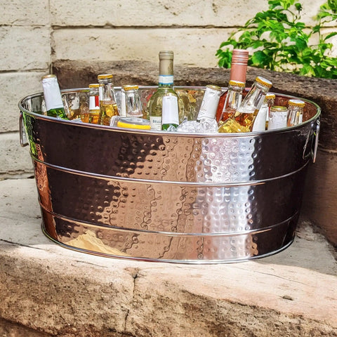 Aspen Heavy-Duty Oval Stainless Steel Drink Cooler For Parties 25-Quart Large Ice Bucket, filled with bottles, on a outdoor surface