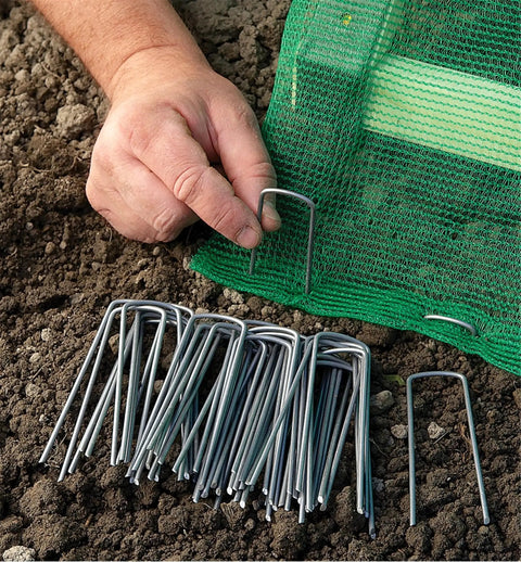 Hand installing 100 Pack 6 Inch Garden Stakes Galvanized Landscape Staples For Weed Barrier Fabric Heavy Duty Sod Pins