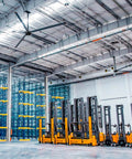 Heavy Duty 16Ft Hvls Industrial Ceiling Fan With 208 240V Three Phase powers large warehouse with forklifts and shelving.
