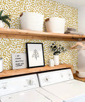 Interior with yellow polka dot peel and stick wallpaper for walls dope home decor, washing machine beneath wooden shelves.