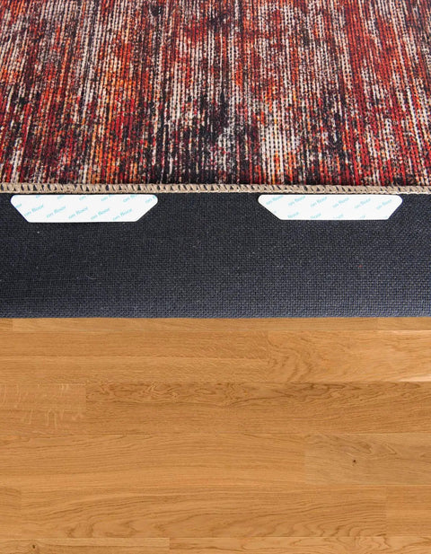 12 Pack Rug Tape No Slip Rug Pad Reusable Washable Grippers beneath patterned rug on hardwood floor