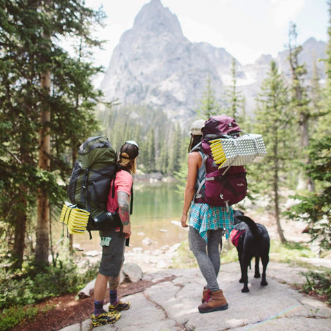 Two hikers with Z Lite Original Camping And Backpacking Sleeping Pad Lightweight Closed Cell Foam Ground Pad in the forest