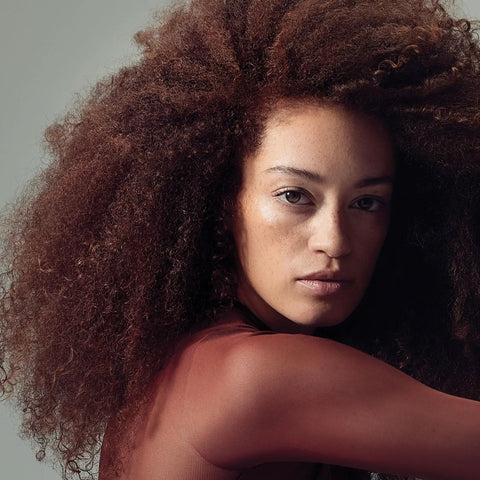 Model with curly hair showcasing the effects of Twirl Around Cream Serum For Curly And Wavy Hair With Frizz Control And Soft Touchable Hold A Cream Gel Hybrid That Defines Curls, Boosts Definition And Bounce, 5.1 Fl Oz.
